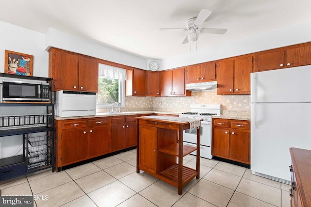 kitchen featuring white appliances, a sink, light countertops, under cabinet range hood, and backsplash