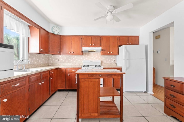 kitchen with under cabinet range hood, light countertops, light tile patterned floors, white appliances, and a sink