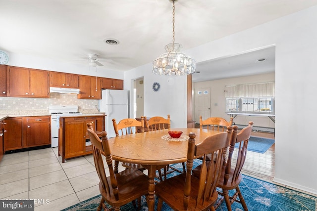 dining area with light tile patterned floors, visible vents, and ceiling fan with notable chandelier