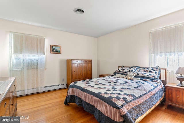 bedroom featuring light wood-type flooring, visible vents, and a baseboard radiator