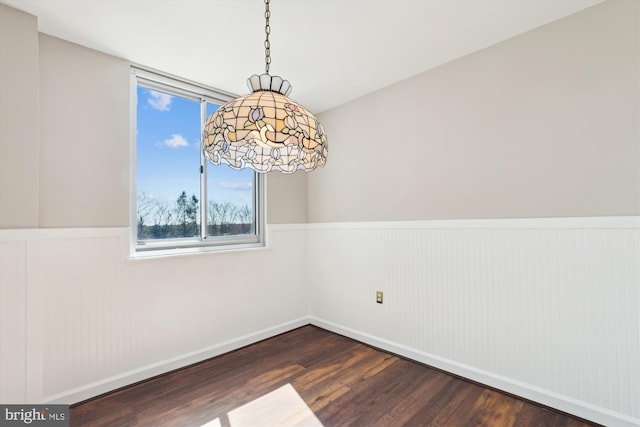 unfurnished dining area featuring wood finished floors and a wainscoted wall