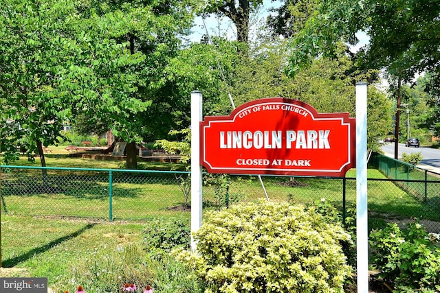 community / neighborhood sign featuring a yard and fence