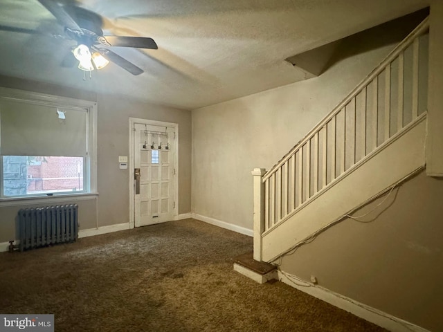 foyer with carpet floors, radiator, baseboards, ceiling fan, and stairs