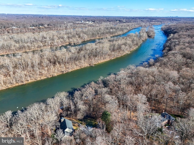 drone / aerial view featuring a wooded view and a water view