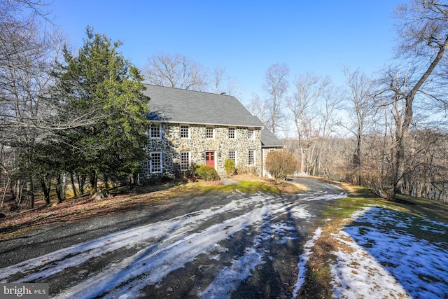 view of front of home featuring stone siding and dirt driveway