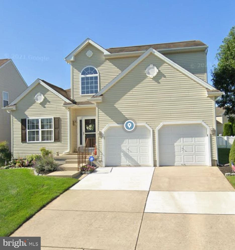 traditional-style house featuring a front lawn, an attached garage, and driveway