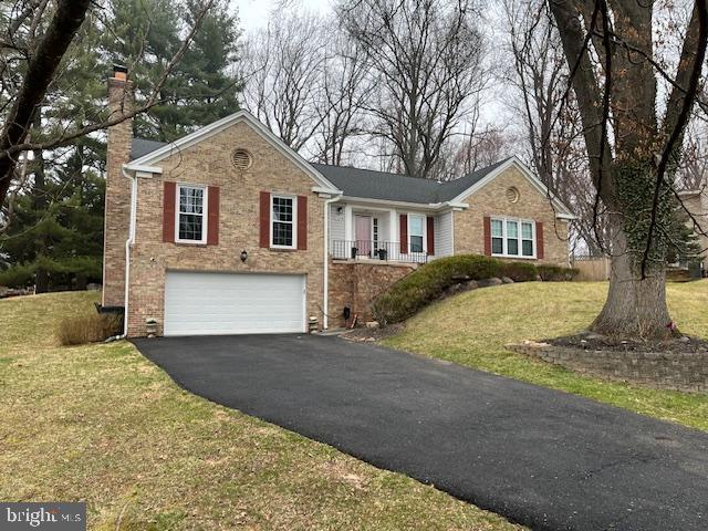 ranch-style home with brick siding, aphalt driveway, a front yard, a chimney, and a garage