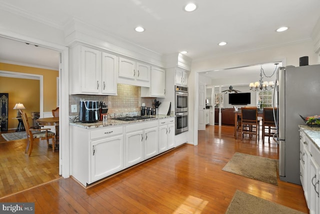 kitchen featuring light wood finished floors, decorative backsplash, white cabinetry, and stainless steel appliances