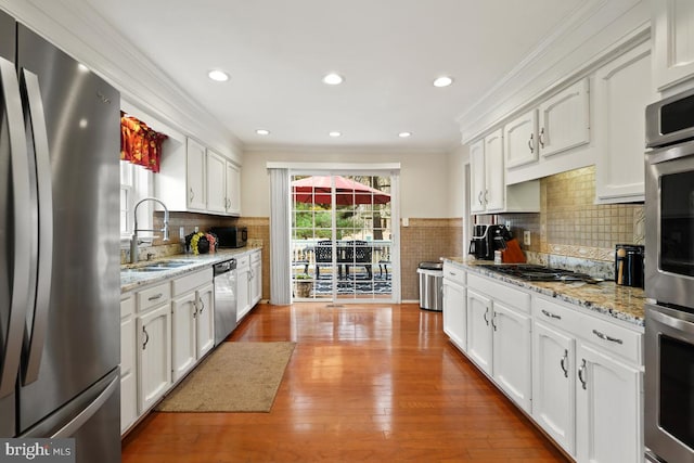 kitchen with ornamental molding, appliances with stainless steel finishes, white cabinetry, and a sink