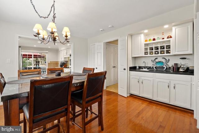 dining room with indoor wet bar, recessed lighting, light wood-style floors, and a chandelier