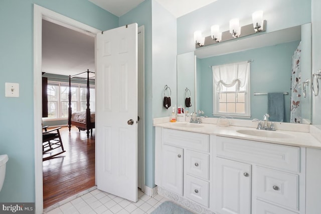 full bathroom with a sink, ensuite bath, double vanity, and tile patterned floors