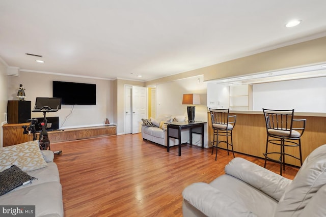 living area with visible vents, recessed lighting, light wood-style floors, and ornamental molding