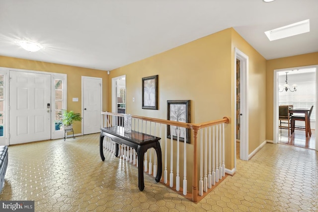 foyer with a chandelier, a skylight, and baseboards