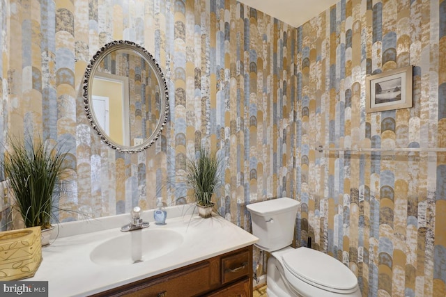 bathroom with wallpapered walls, toilet, and vanity