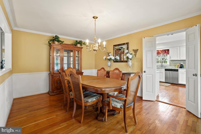 dining room featuring light wood-type flooring, an inviting chandelier, and crown molding