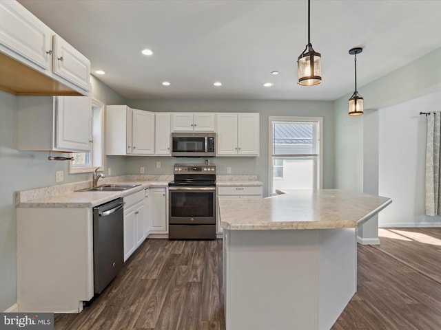 kitchen with a sink, dark wood-type flooring, appliances with stainless steel finishes, and white cabinetry