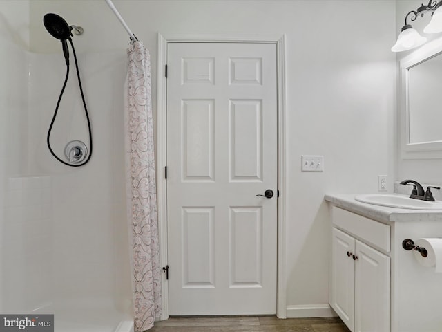 bathroom featuring vanity, a shower with shower curtain, wood finished floors, and baseboards