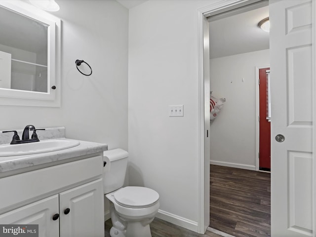 bathroom featuring vanity, toilet, wood finished floors, and baseboards