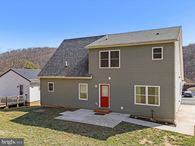 rear view of property featuring a yard, a patio, a shingled roof, and entry steps