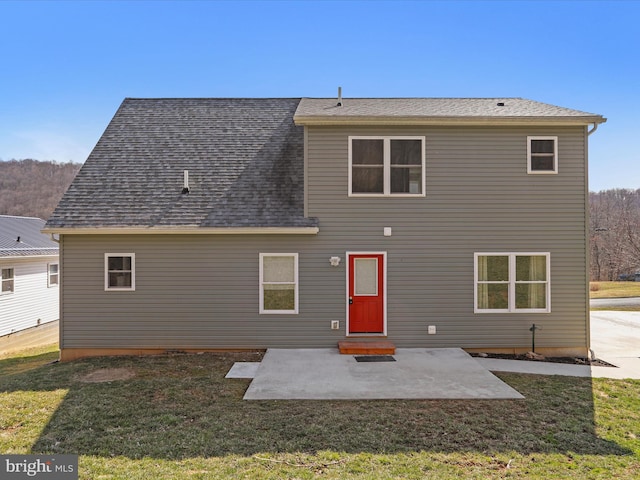 rear view of property featuring a patio area, a lawn, and a shingled roof