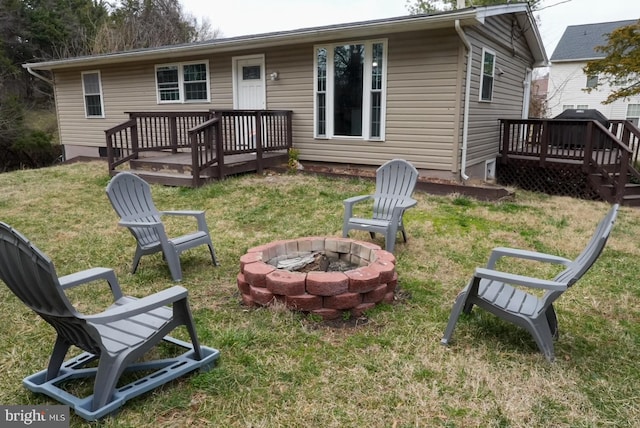 rear view of house with a yard, an outdoor fire pit, and a deck