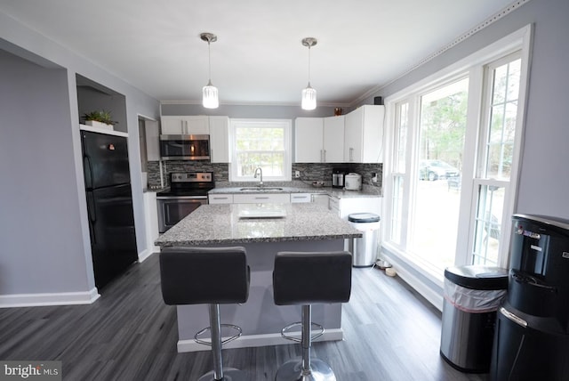 kitchen featuring white cabinets, appliances with stainless steel finishes, a center island, and a sink