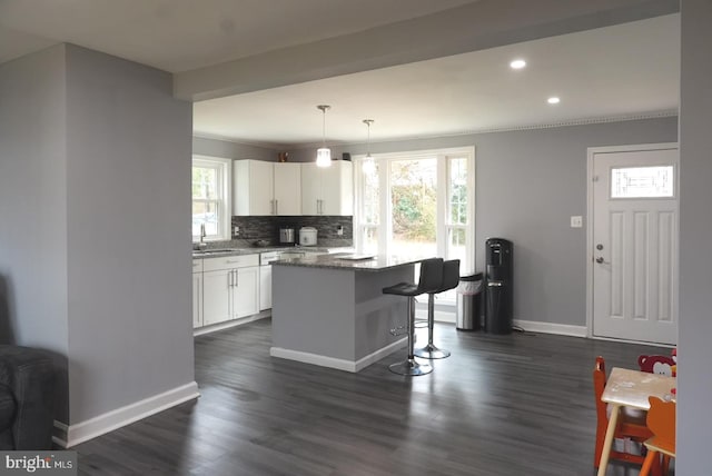 kitchen with a breakfast bar area, white cabinets, tasteful backsplash, and a wealth of natural light