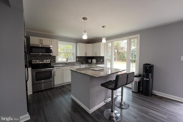 kitchen featuring a sink, decorative backsplash, appliances with stainless steel finishes, and white cabinetry