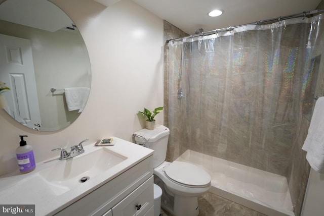 bathroom with vanity, toilet, and tiled shower