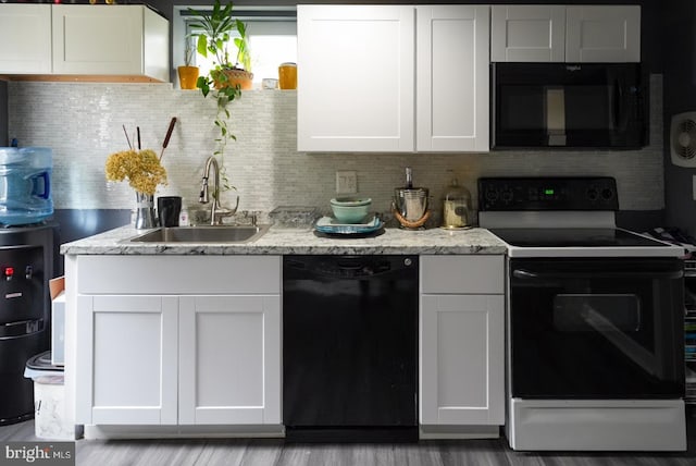 kitchen with black appliances, a sink, light stone counters, tasteful backsplash, and white cabinetry