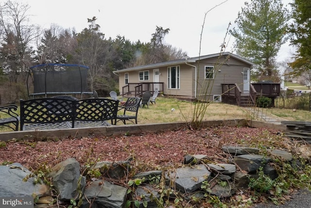 rear view of house with a deck and a trampoline