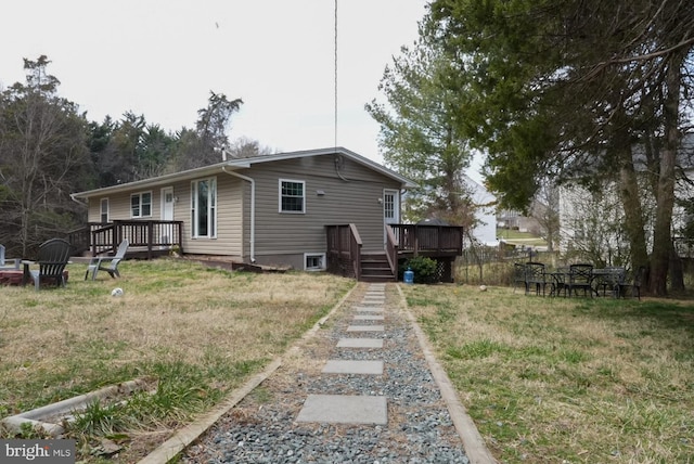 rear view of house featuring a lawn and a wooden deck