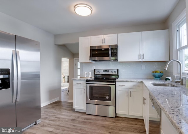 kitchen with a sink, stainless steel appliances, and white cabinetry