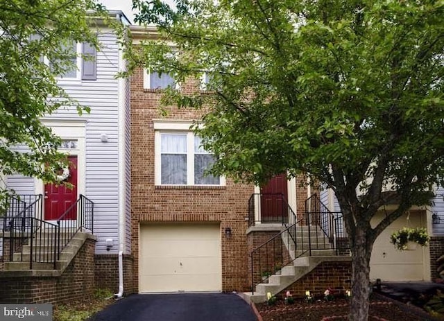 townhome / multi-family property featuring aphalt driveway, an attached garage, and brick siding