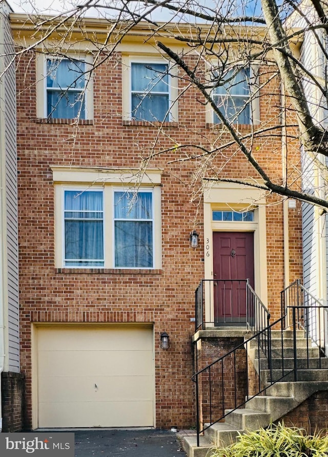 view of front facade featuring driveway, brick siding, and an attached garage