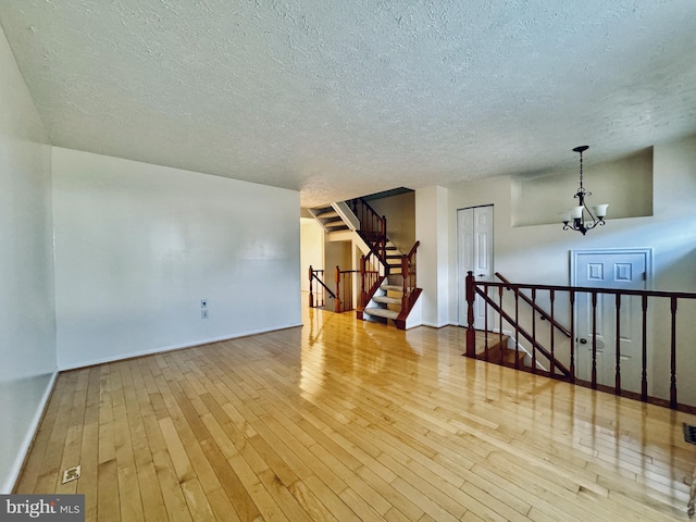 empty room featuring stairs, baseboards, wood-type flooring, and a chandelier