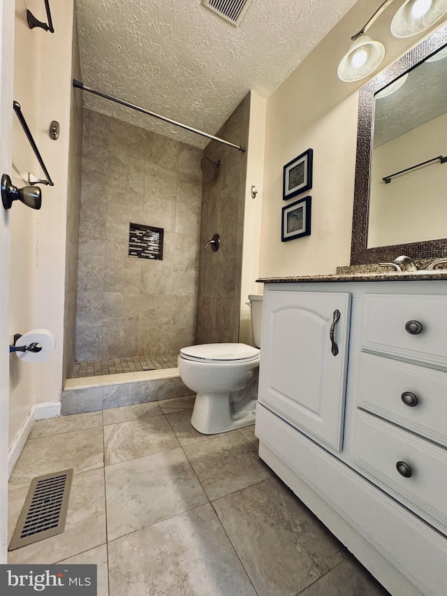 bathroom with visible vents, a textured ceiling, toilet, and tiled shower