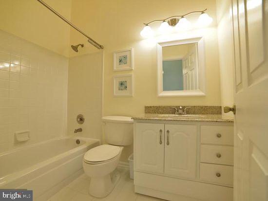 full bath with vanity, tile patterned floors, toilet, and shower / washtub combination