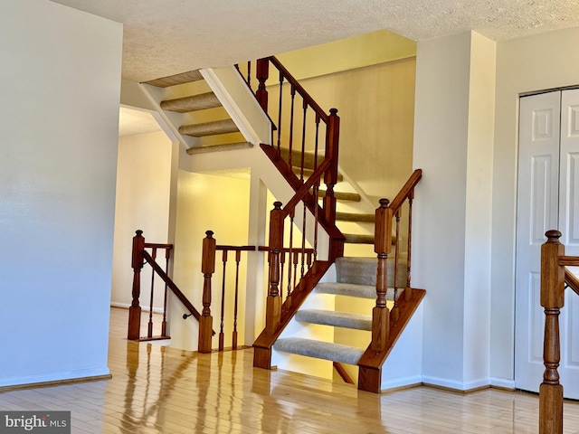 stairway featuring a textured ceiling, baseboards, and hardwood / wood-style flooring