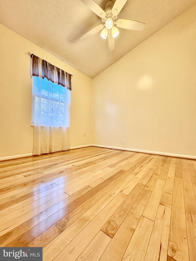 spare room featuring hardwood / wood-style floors, a textured ceiling, vaulted ceiling, and ceiling fan