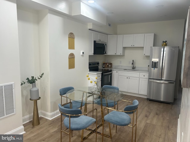 kitchen featuring light wood finished floors, stainless steel appliances, light countertops, and a sink