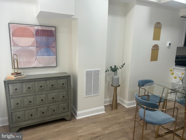 dining space with light wood-type flooring, visible vents, and baseboards