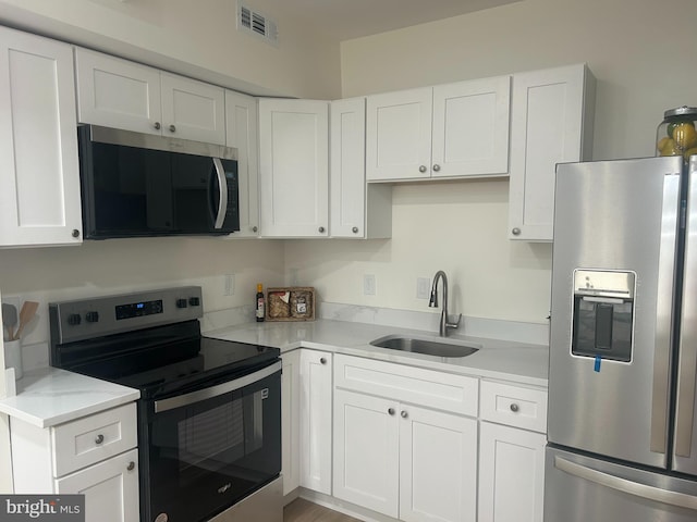 kitchen with visible vents, light countertops, appliances with stainless steel finishes, white cabinetry, and a sink