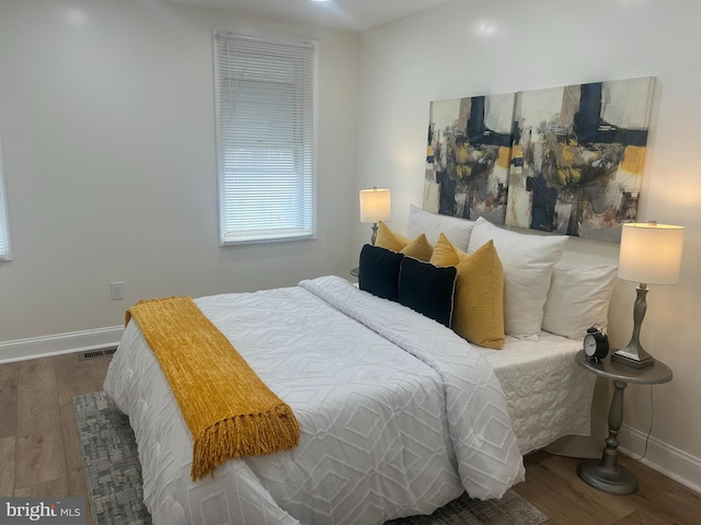 bedroom featuring visible vents, baseboards, and wood finished floors