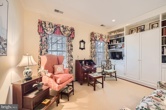 sitting room with visible vents, carpet floors, and ornamental molding