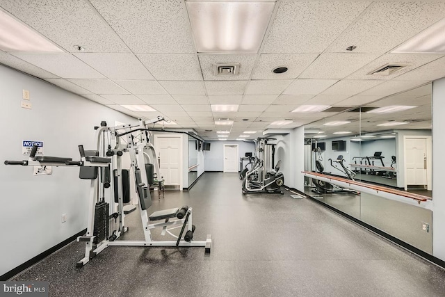 gym with a paneled ceiling, baseboards, and visible vents