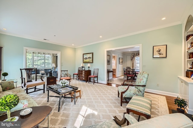 living area with baseboards, a healthy amount of sunlight, light wood-style flooring, and crown molding