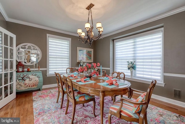 dining space featuring baseboards, wood finished floors, an inviting chandelier, and ornamental molding