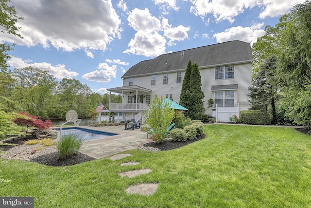 back of property featuring a yard, a patio area, and an outdoor pool