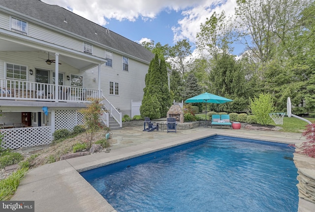 outdoor pool with a patio area, an outdoor living space with a fireplace, stairs, and a ceiling fan